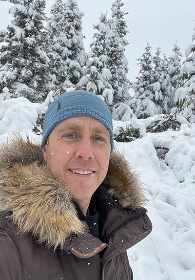 Smiling man wearing ski cap and coat in snowy landscape