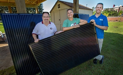 Three FSU alumni holding a solar panel
